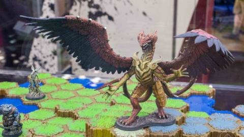 A dragon stands over a set of hex-shaped tiles.