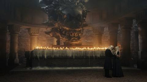 Viserys talking to his daughter in front of an altar with a bunch of candles and a giant dragon skull in House of the Dragon