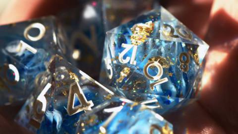 Blue and gold-flecked dice refract light into the holder’s hand. 