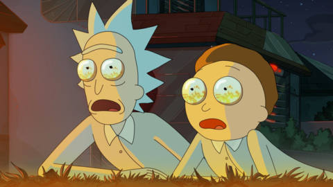 Rick and Morty lying on the ground staring in shock with flames reflected in their eyes