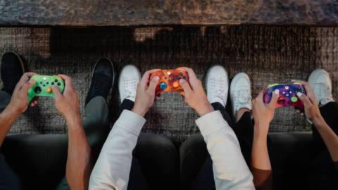 A stock image featuring three people holding the new Xbox wireless controllers