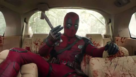 Deadpool taunts unseen adversaries as he sits bleeding in the back of a car while holding a knife in Deadpool &amp; Wolverine