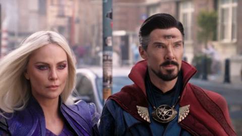 Clea (Charlize Theron) and Stephen Strange (Benedict Cumberbatch) look toward a portal on the streets of New York in a shot form Doctor Strange in the Multiverse of Madness. He’s got a third photorealistic eye on his forehead.