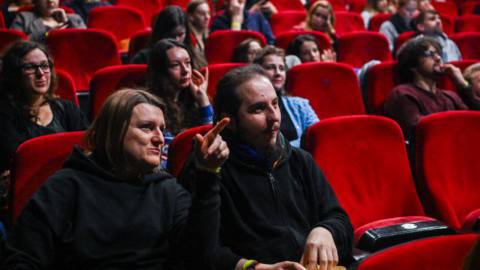 People enjoy popcorn as they watch a live screening