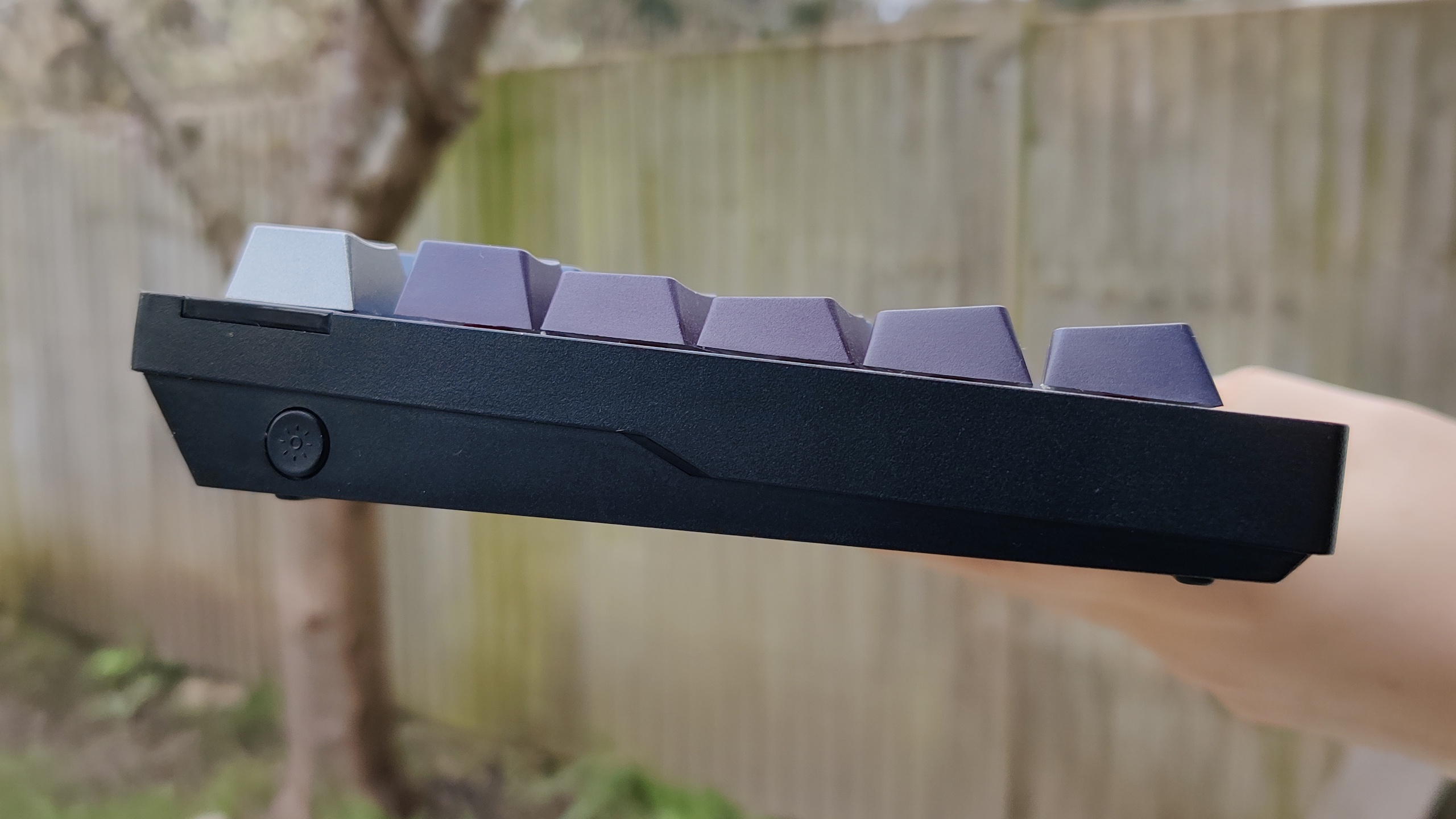 Corsair K65 pictured outdoors with black and grey keycaps.