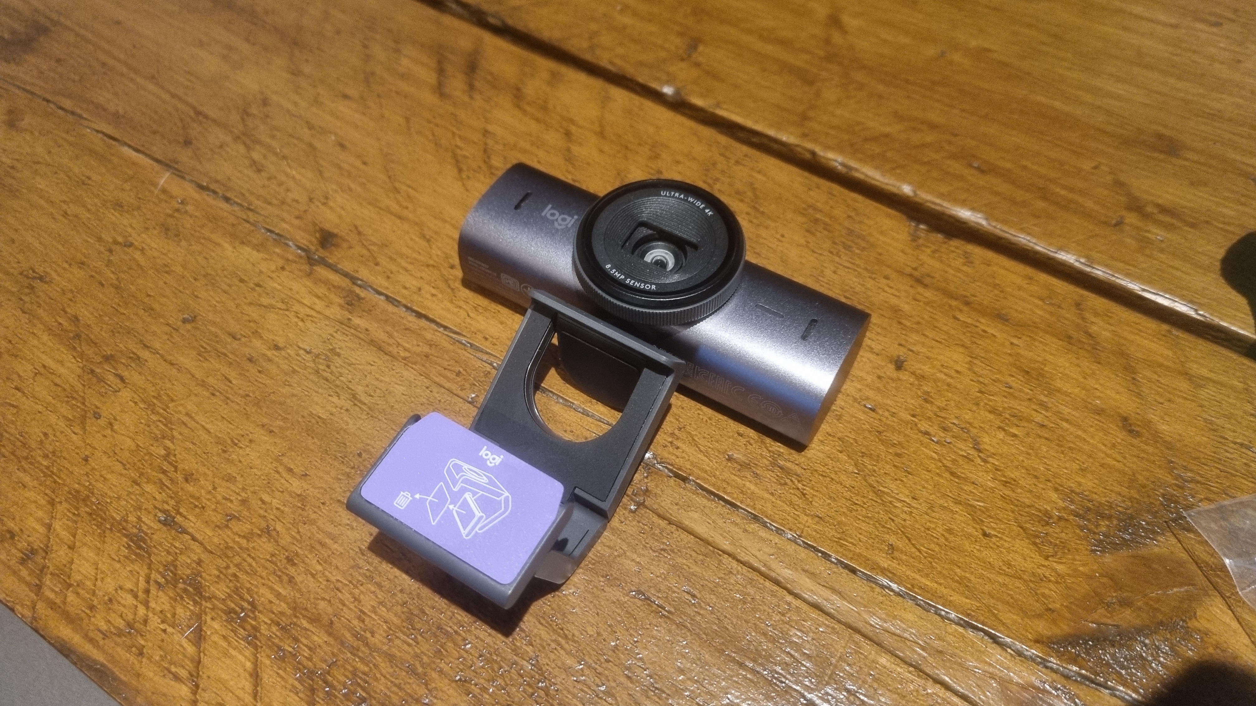 The Logitech MX Brio webcam on a wooden desk with its mount opened