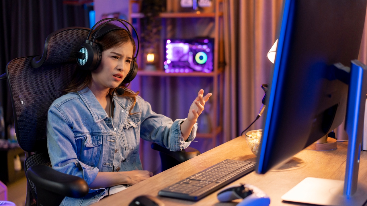 A young woman gestures at her screen while gaming.