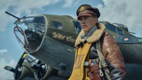 Austin Butler’s character in Masters of the Air standing in front of a bomber jet