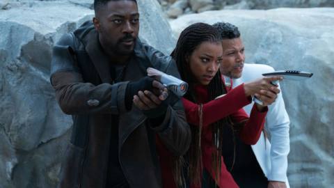 David Ajala and Sonequa Martin-Green hold up Star Trek phasers, standing next to Wilson Cruz on a rocky planet in Star Trek: Discovery