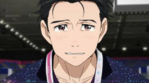 A dark-haired male figure skater crying on the rink