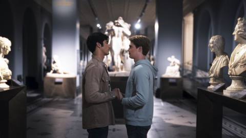 Alex and Henry standing in an empty museum, holding hands