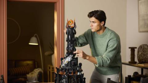 A man in a green shirt builds the tower of Barad-dûr from the new Lord of the Rings: Barad-Dûr Lego set