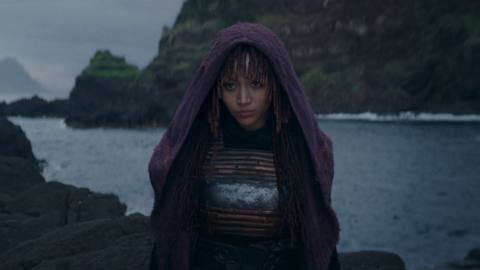 Amandla Stenberg looking vaguely evil over a cliff face in front of water in The Acolyte