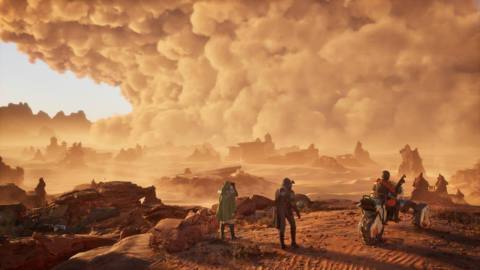 Three people in desert wear face away from the camera, gazing out at a vista on the desert planet of Arrakis from Dune: Awakening