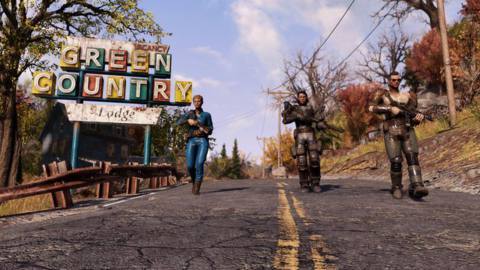 A trio of wasteland survivors walk down a country road in Fallout 76, passing the Green Country Lodge sign and the natural trees of Appalachia.