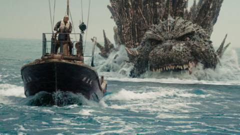 A man aboard a small motorized, wooden boat speed away from the mouth of a colossal spiky creature swimming after him in Godzilla Minus One.