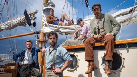 Henry Cavill and the cast of The Ministry of Ungentlemanly Warfare stand around looking manly on a boat