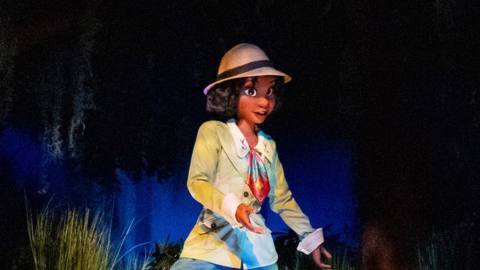 The Tiana animatronic in Walt Disney World’s ride Tiana’s Bayou Adventure wearing a sporty jacket and pants combo, with a hat, as she treks through the bayou.