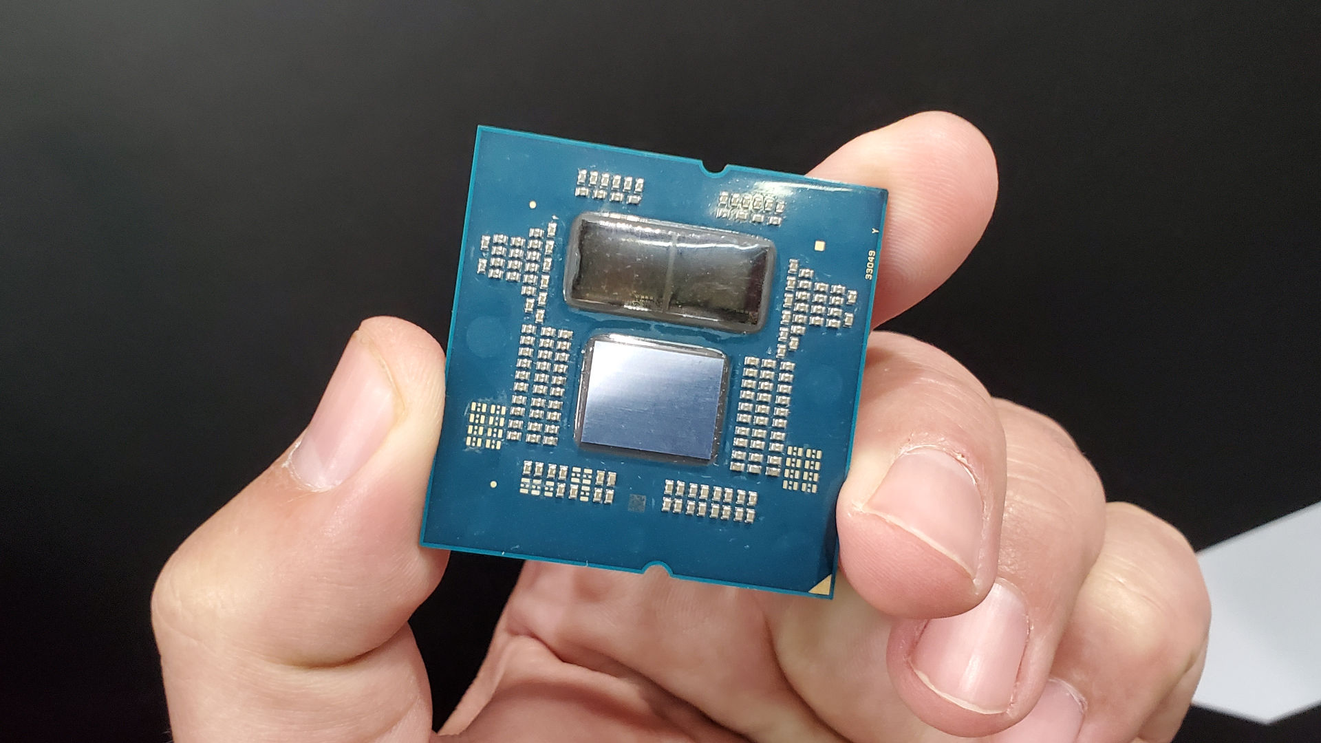 Image of an AMD Ryzen 9000 series processor, with the headspreader removed, held in a hand