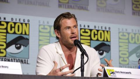 Chris Hemsworth speaks in front of a wall of Comic-Con logos at Paramount Animation’s presentation for Transformers One at 2024’s San Diego Comic-Con