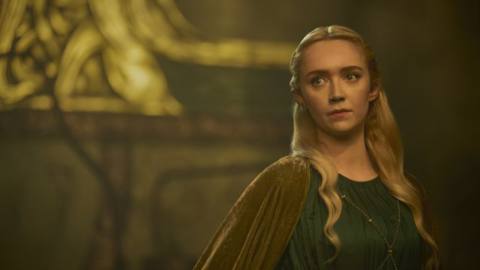 Amelia Kenworthy as Mirdania in Rings of Power. A blond elven character, she’s wearing a green robe and velvet cape. 