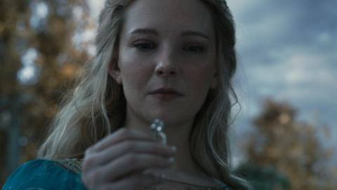 Galadriel holds up one of the elven rings of power and looks at it, in The Lord of the Rings: The Rings of Power. 