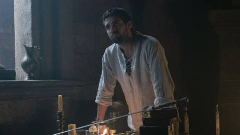 Criston Cole (Fabien Frankel) looking frustrated at a table where he’s cleaning his sword