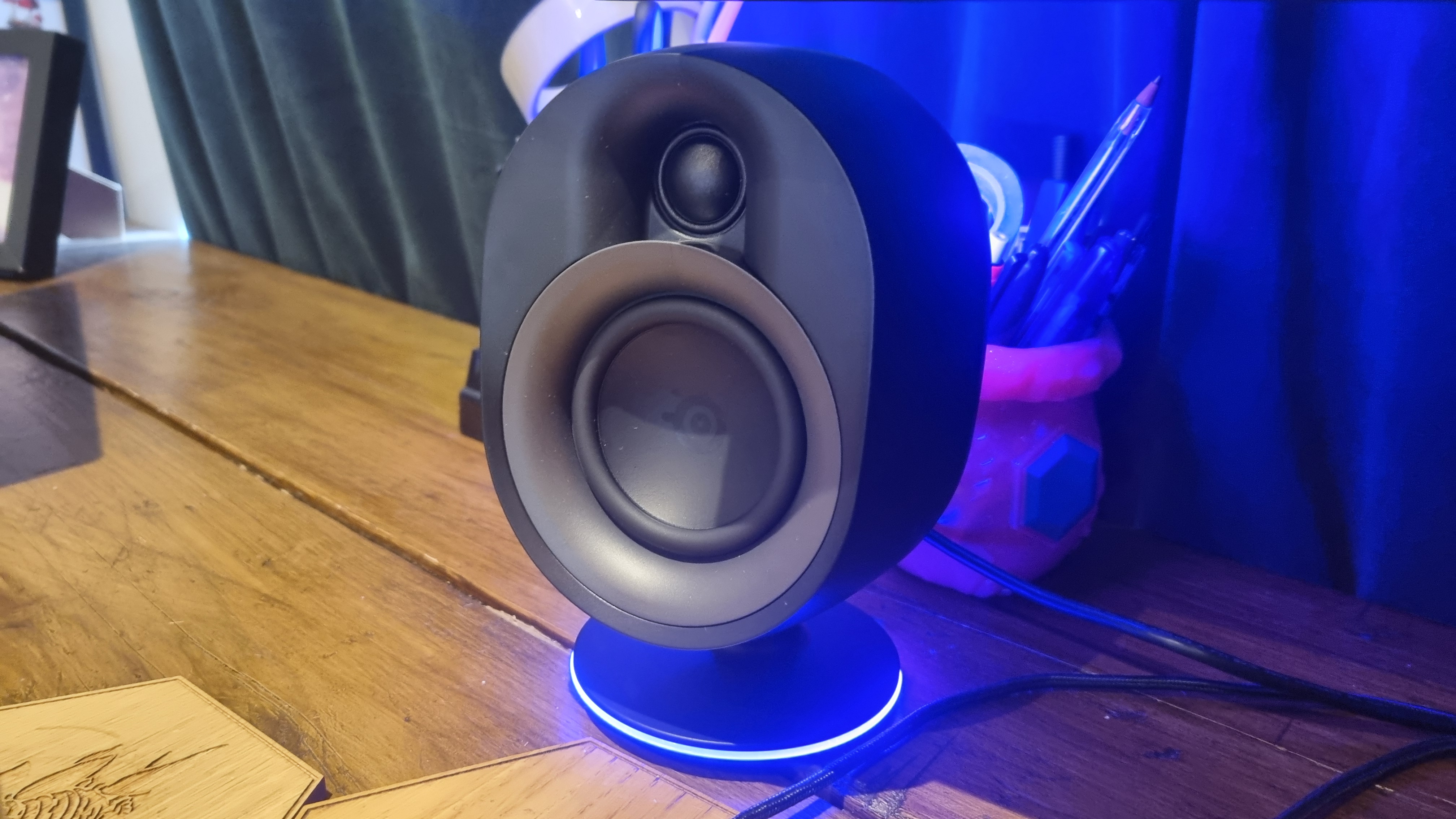 The left front speaker of the SteelSeries Arena 9, lit up in blue