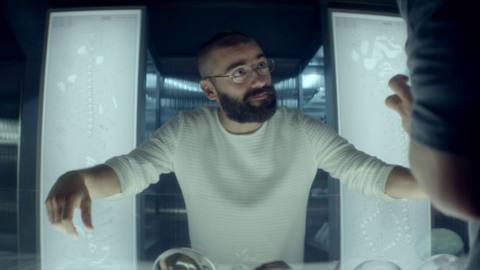 Oscar Isaac stands in front of two bright white lights while wearing a white shirt in Ex Machina