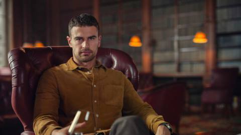 Theo James as Eddie Horniman from The Gentlemen sitting in a plush chair drinking wine