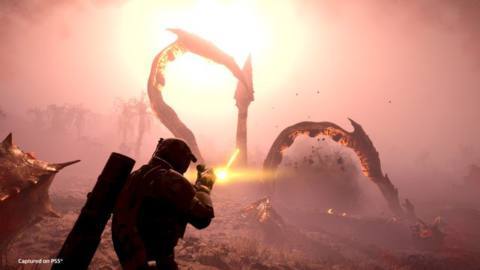 A Helldiver fires his weapon at an Impaler’s spiked tentacles, which kick up dust from the planet as they break out of the earth.