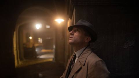 Gereon (Volker Bunch) looks up in a dark shadowy hallway in a still from Babylon Berlin season 4