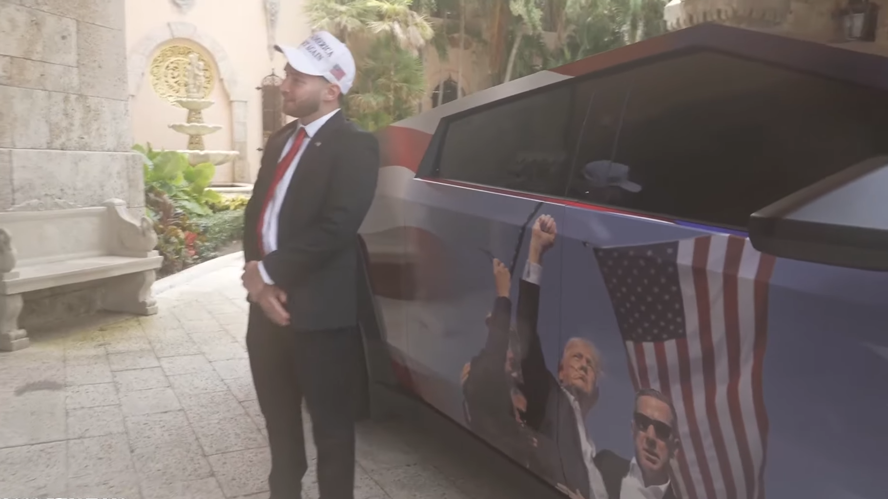 Adin Ross stands next to a customised Cybertruck bearing an image of Trump raising a fist after his assassination attempt.