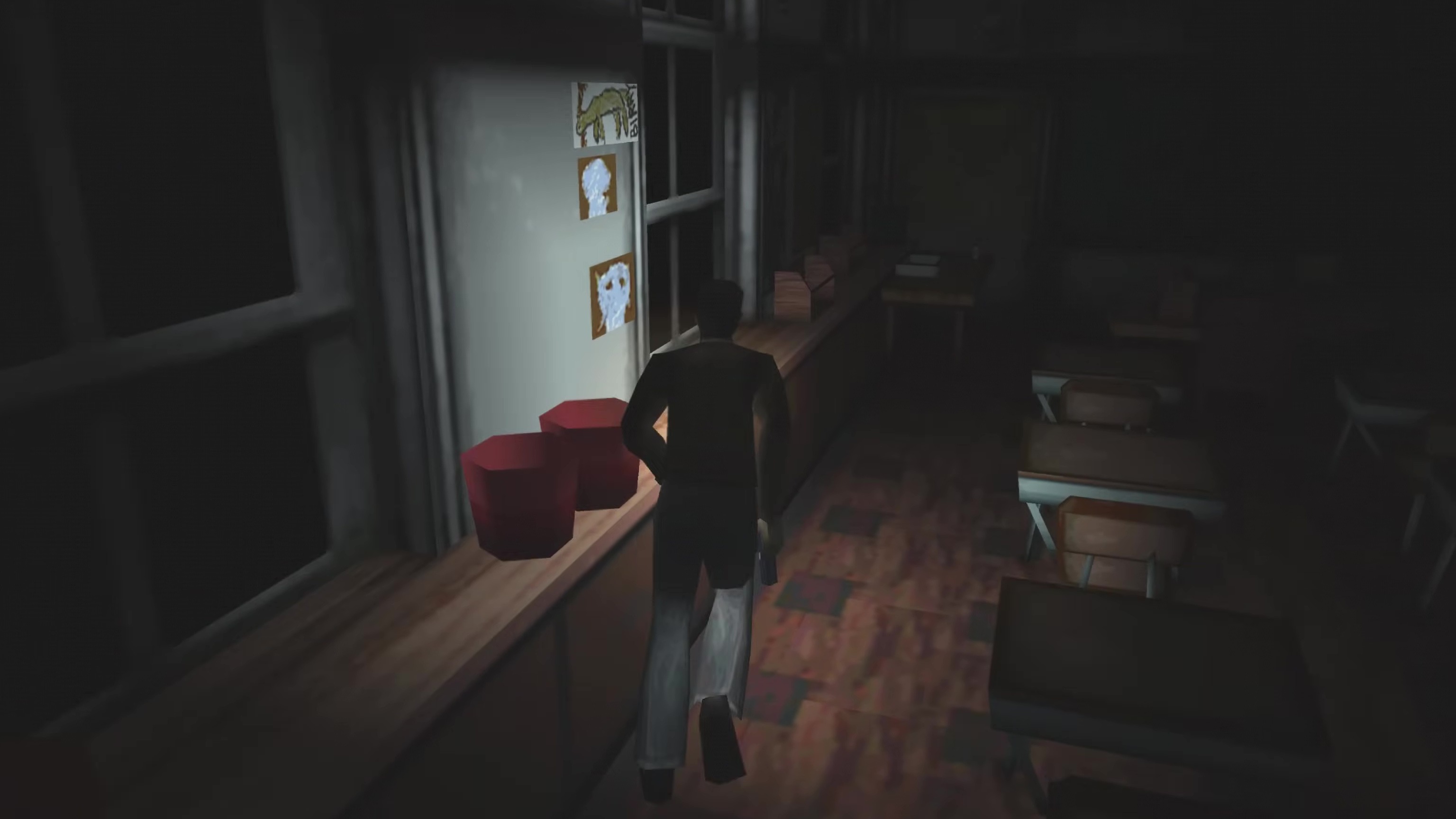 The protagonist of Silent Hill runs through a darkened public school classroom, his pistol in his right hand