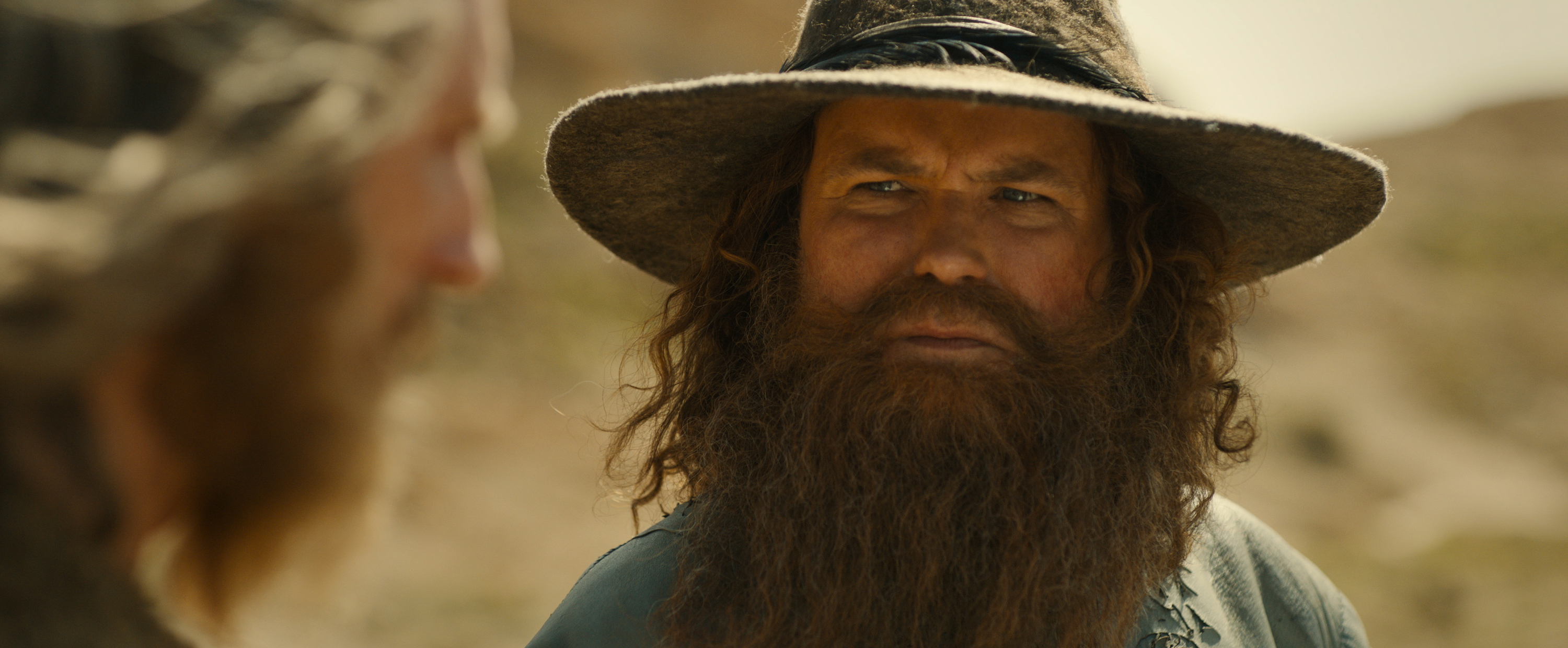 Tom Bombadil in a big hat and beard squinting at The Stranger in The Lord of the Rings: Rings of Power season 2