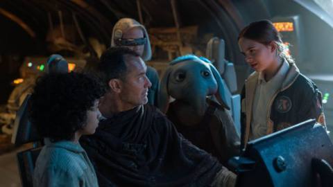 Jude Law Jedi huddles with some kids including a kid Ortolan aka Baby Max Rebo in a spaceship cockpit in Star Wars: Skeleton Crew