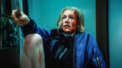 Gretchen (Euphoria’s Hunter Schafer), a teenage girl with her face and hands covered in blood, sits outside against a glass door and waves a knife at an unseen assailant in Tilman Singer’s Cuckoo