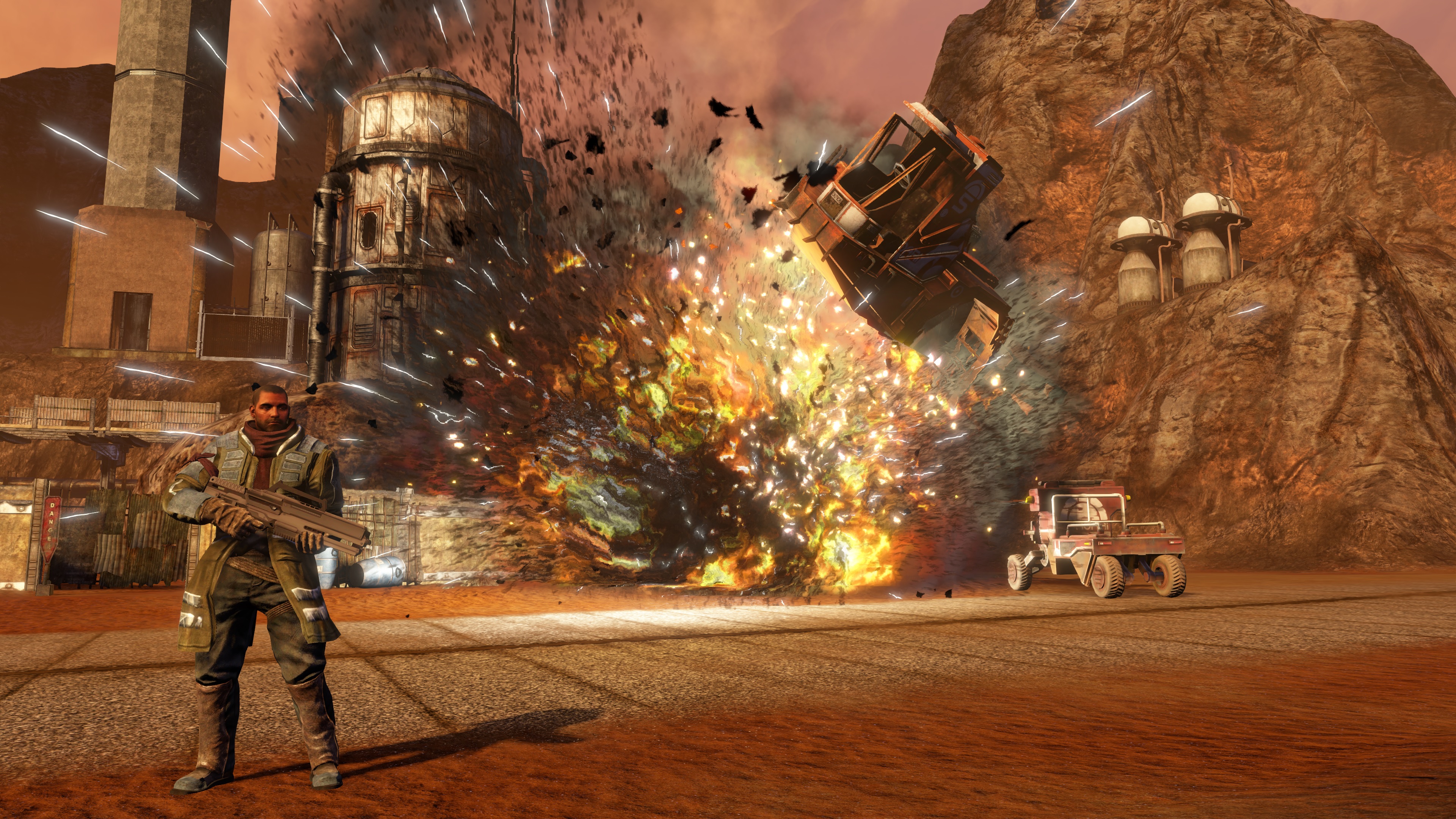 Red Faction: Guerrilla Re-Mars-tered Edition - Alec Mason standing as vehicles explode behind him. Red Faction: Guerrilla Re-Mars-tered Edition - Alec Mason standing as vehicles explode behind him.