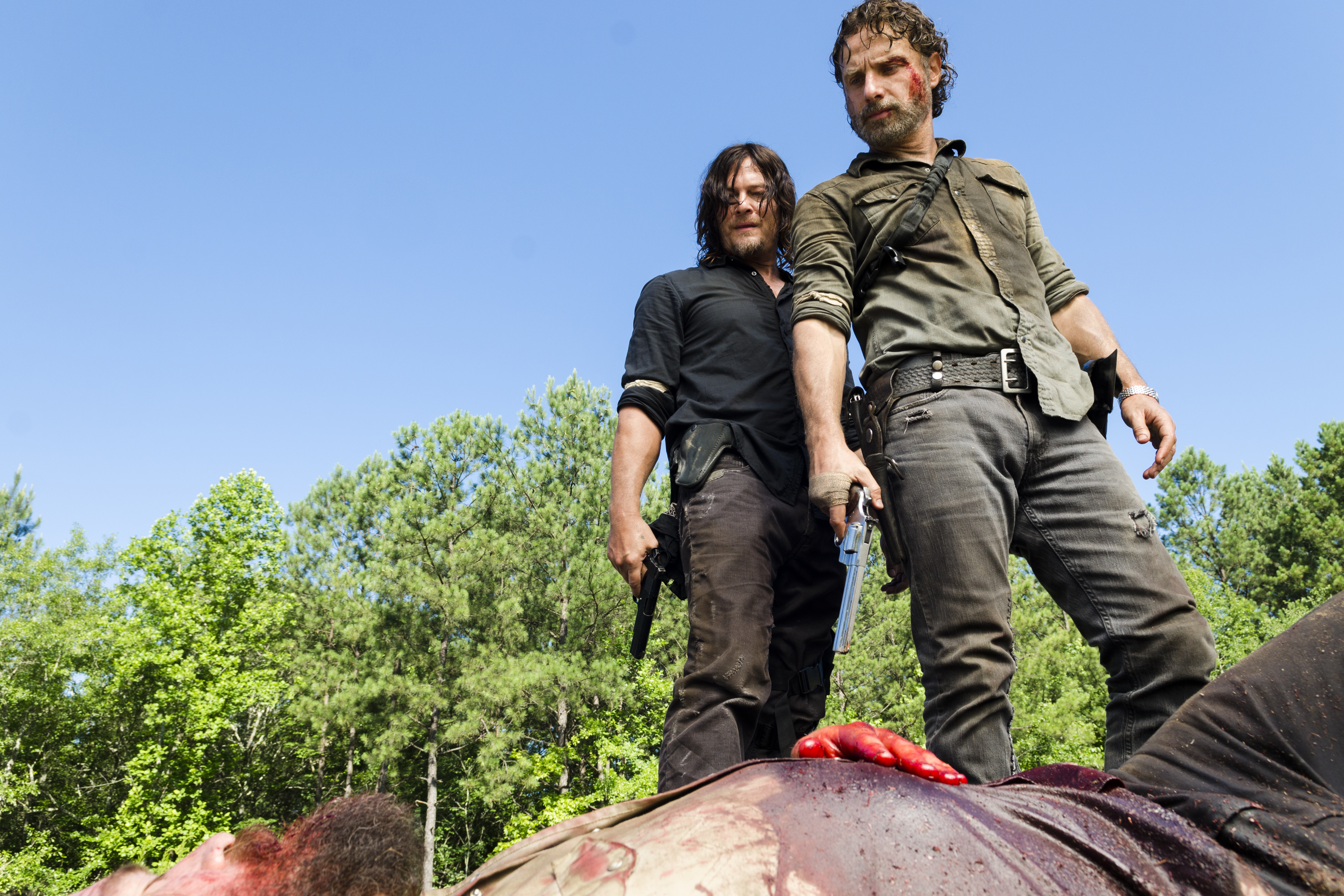 Daryl and Rick standing over a person dying looking down at them