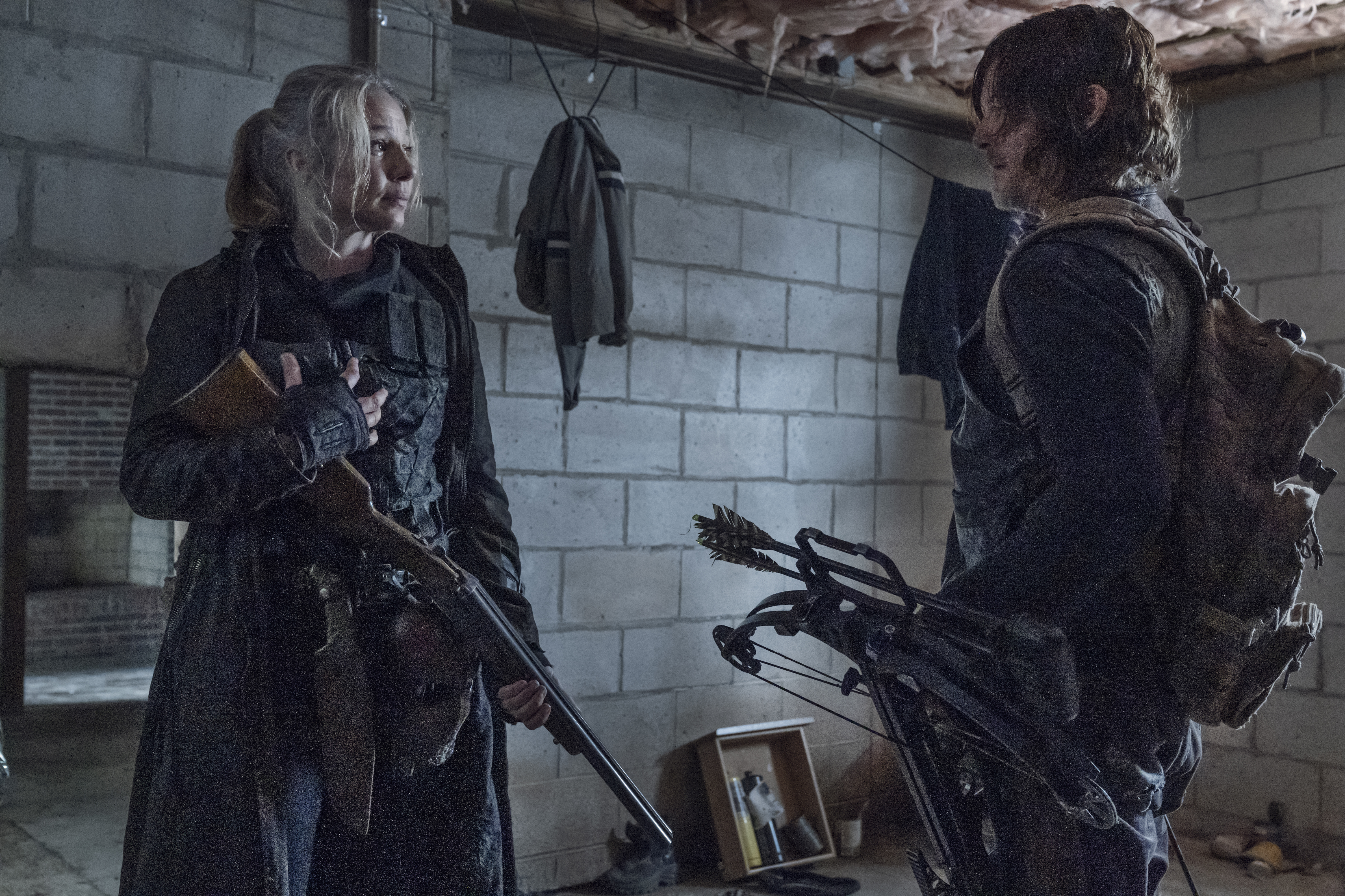 Leah and Daryl standing with guns looking at each other