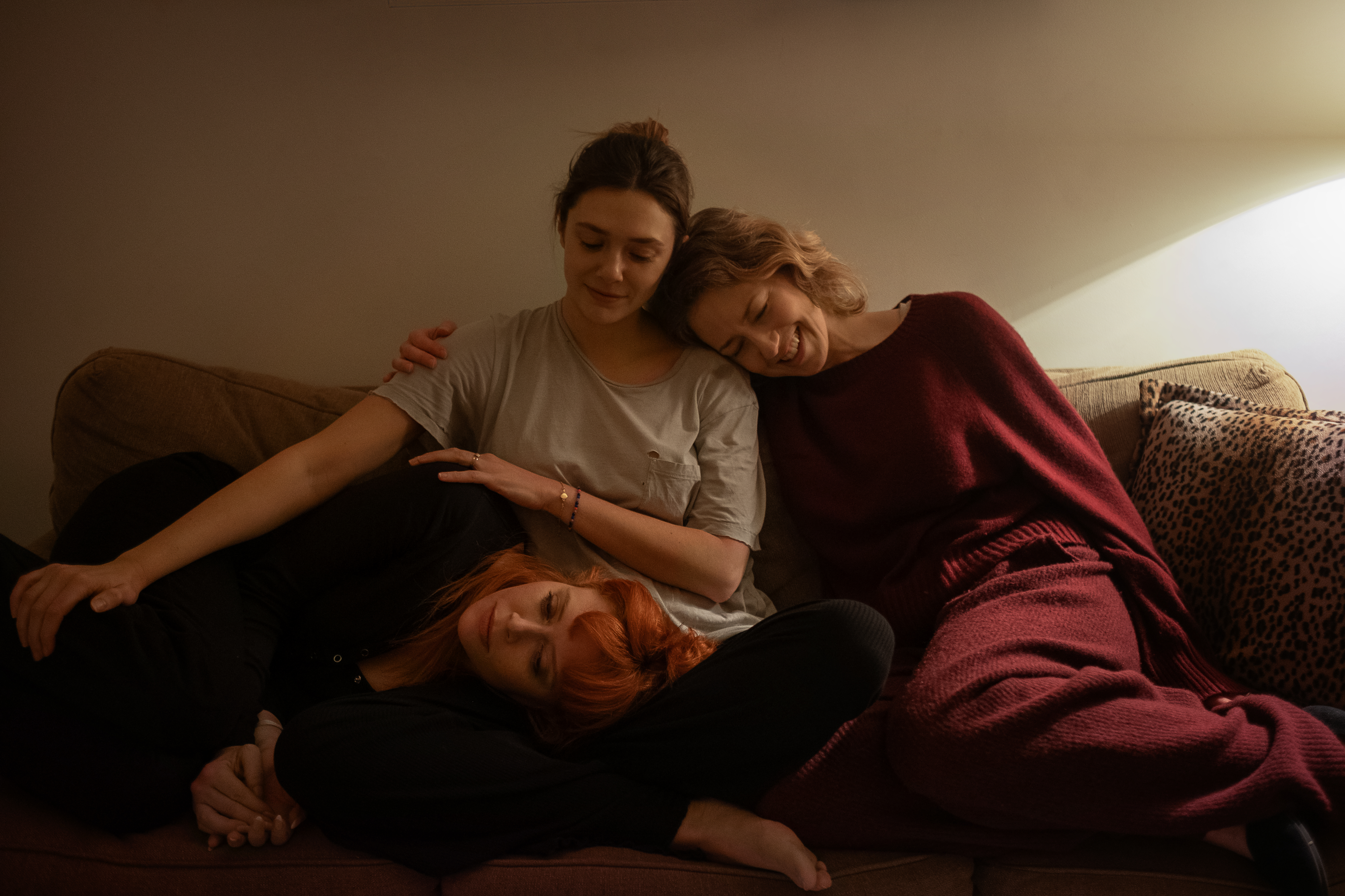 Natasha Lyonne, Elizabeth Olsen, and Carrie Coon sitting on a couch in His Three Daughters.