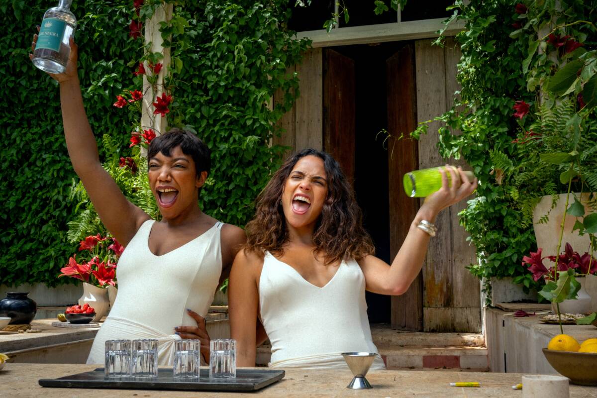 Two women holding drink shakers and screaming happily in Blink Twice.