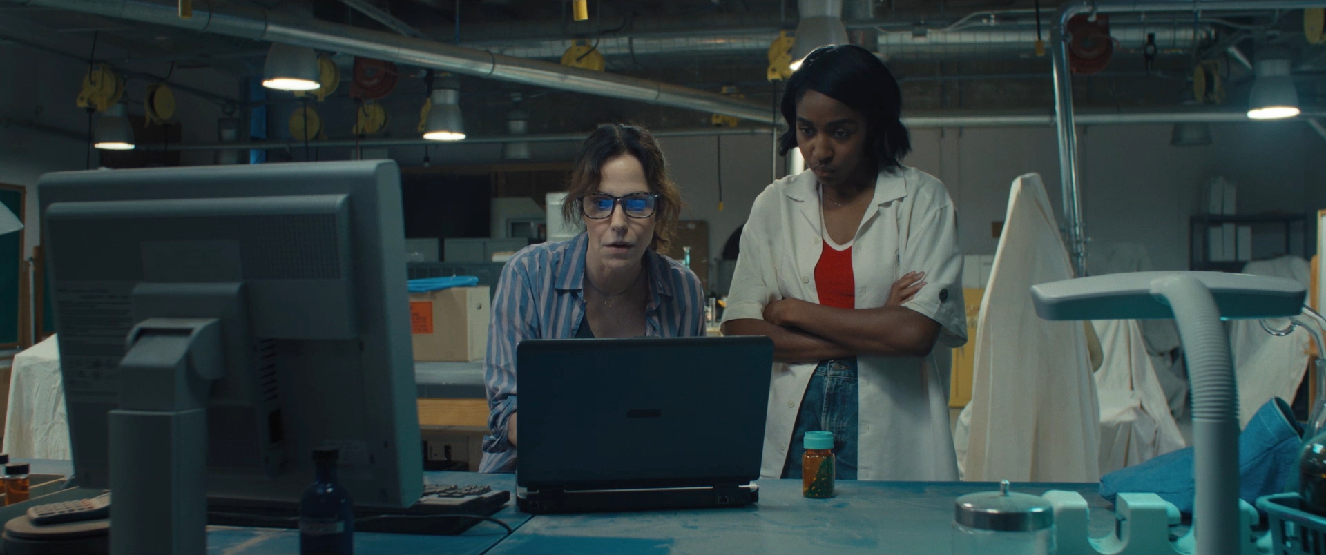 Two woman staring intensely at a computer monitor in a cluttered laboratory in Omni Loop.