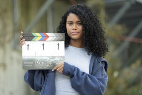 Tamara Smart, a young Black woman with dark curly hair, holds up a clapboard
