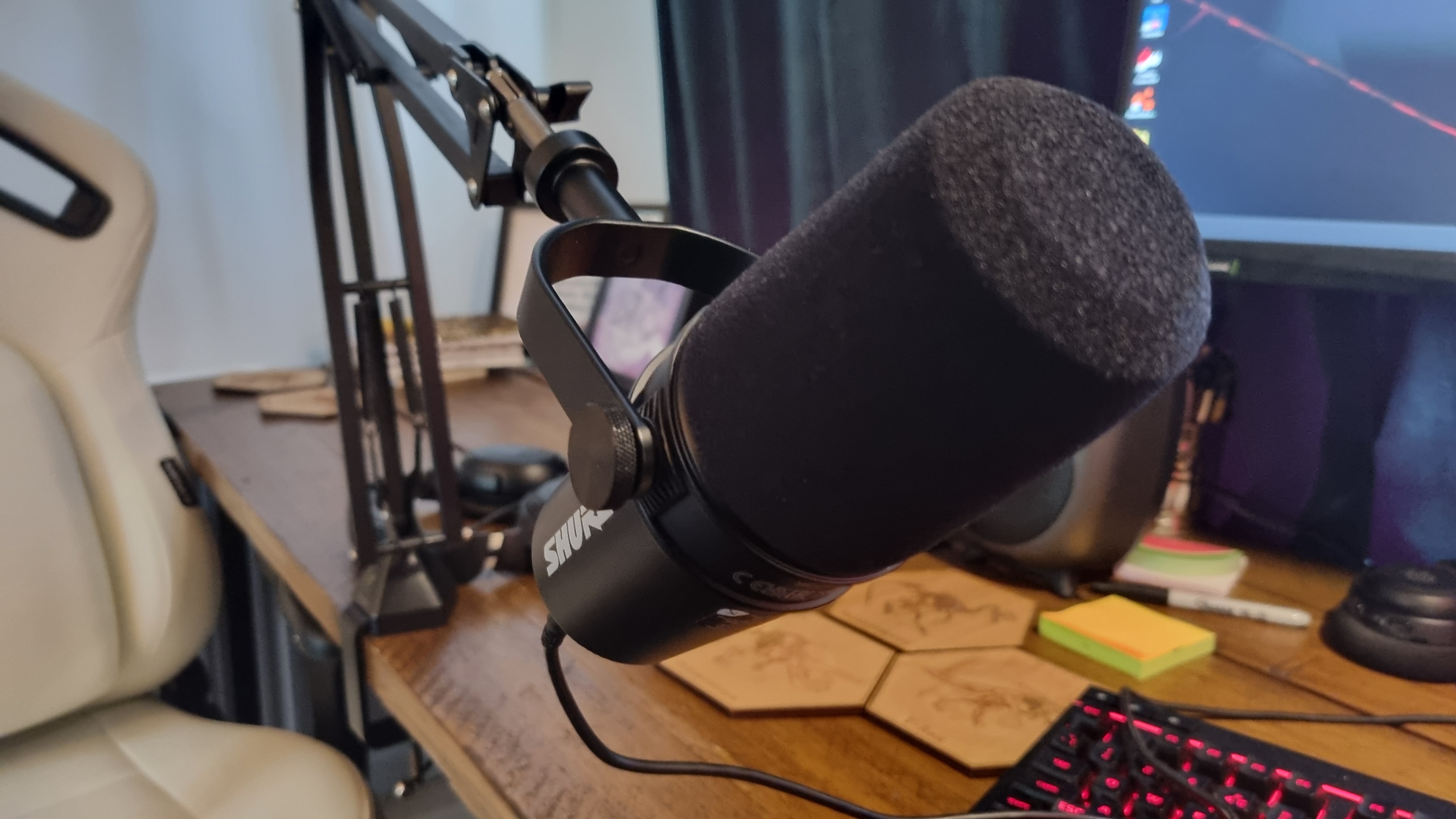 The Shure MV7+ Podcast Microphone attached to a boom arm