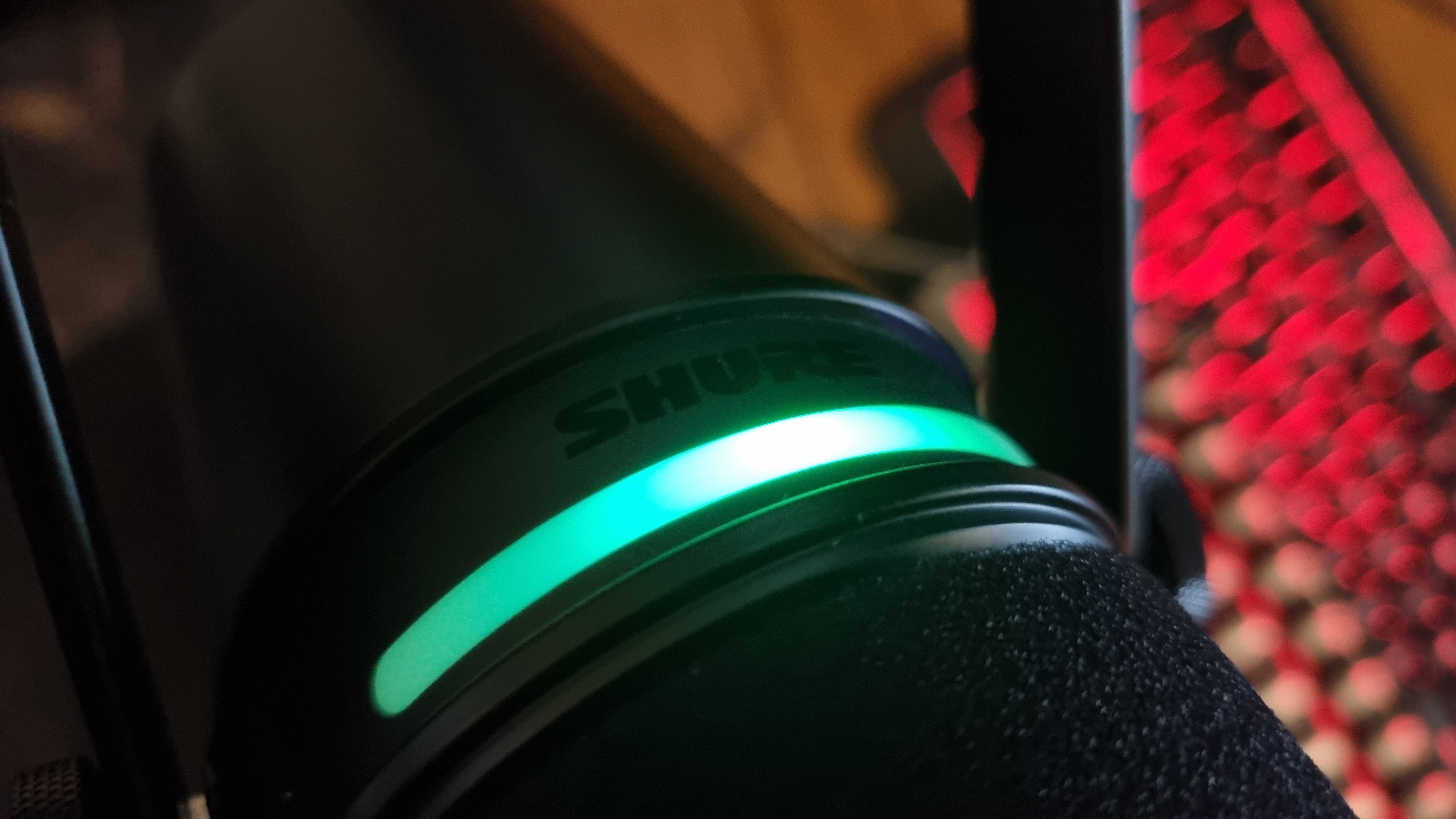 The top of the Shure MV7+ Podcast Microphone, showing the RGB touch controls lit-up in green