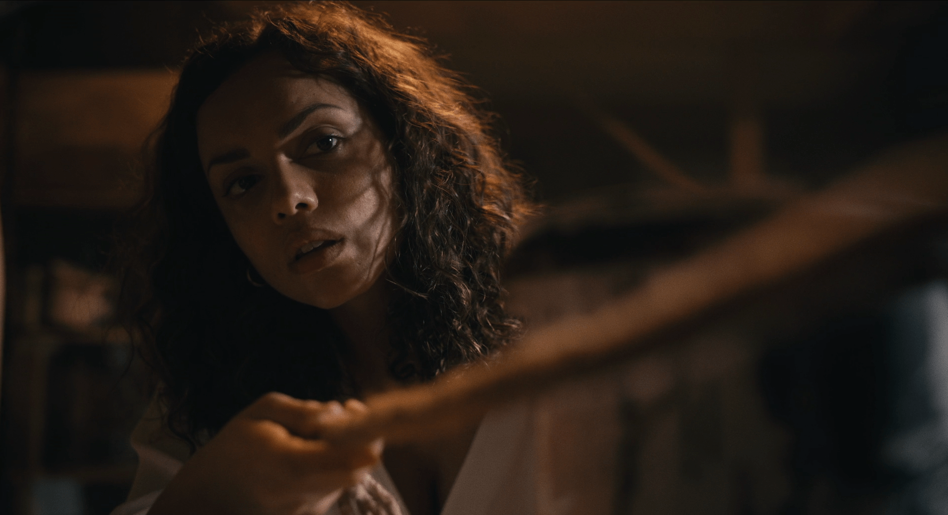 Georgina Campbell looks curious while pulling on rope in a dark, close space in Barbarian