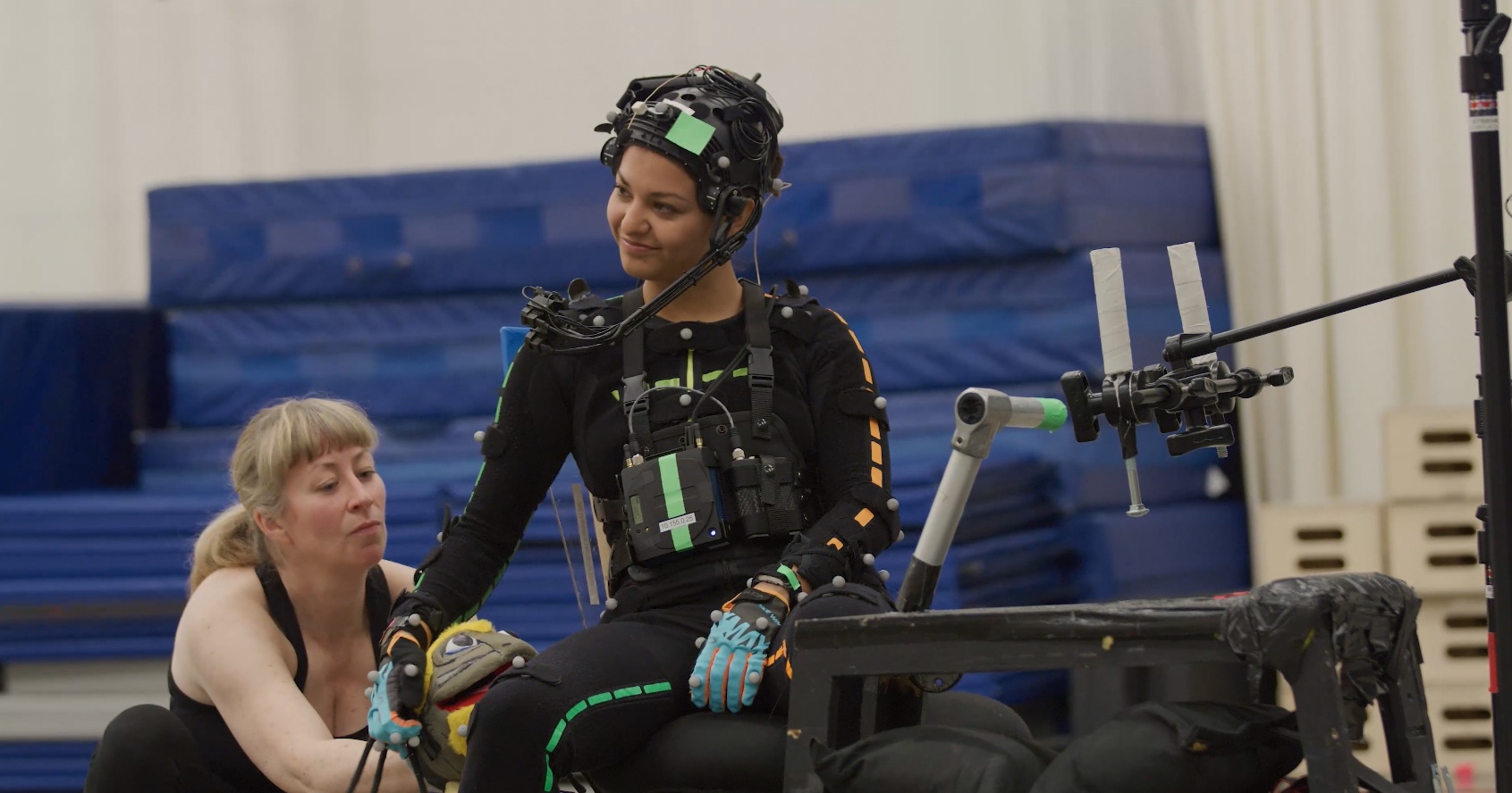 Humberly González in a motion-capture suit petting a Nix puppet while a puppeteer controls the creature