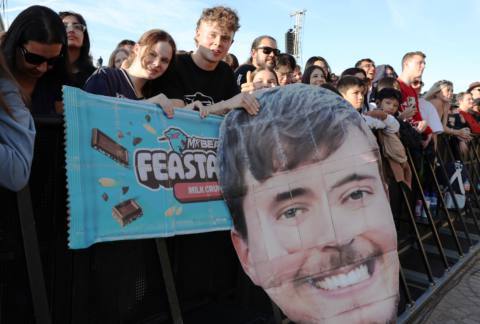 Fans holding Feastables signs and a MrBeast hed look on during the MrBeast Feastables launch at Sydney Opera House on June 26, 2024 in Sydney, Australia