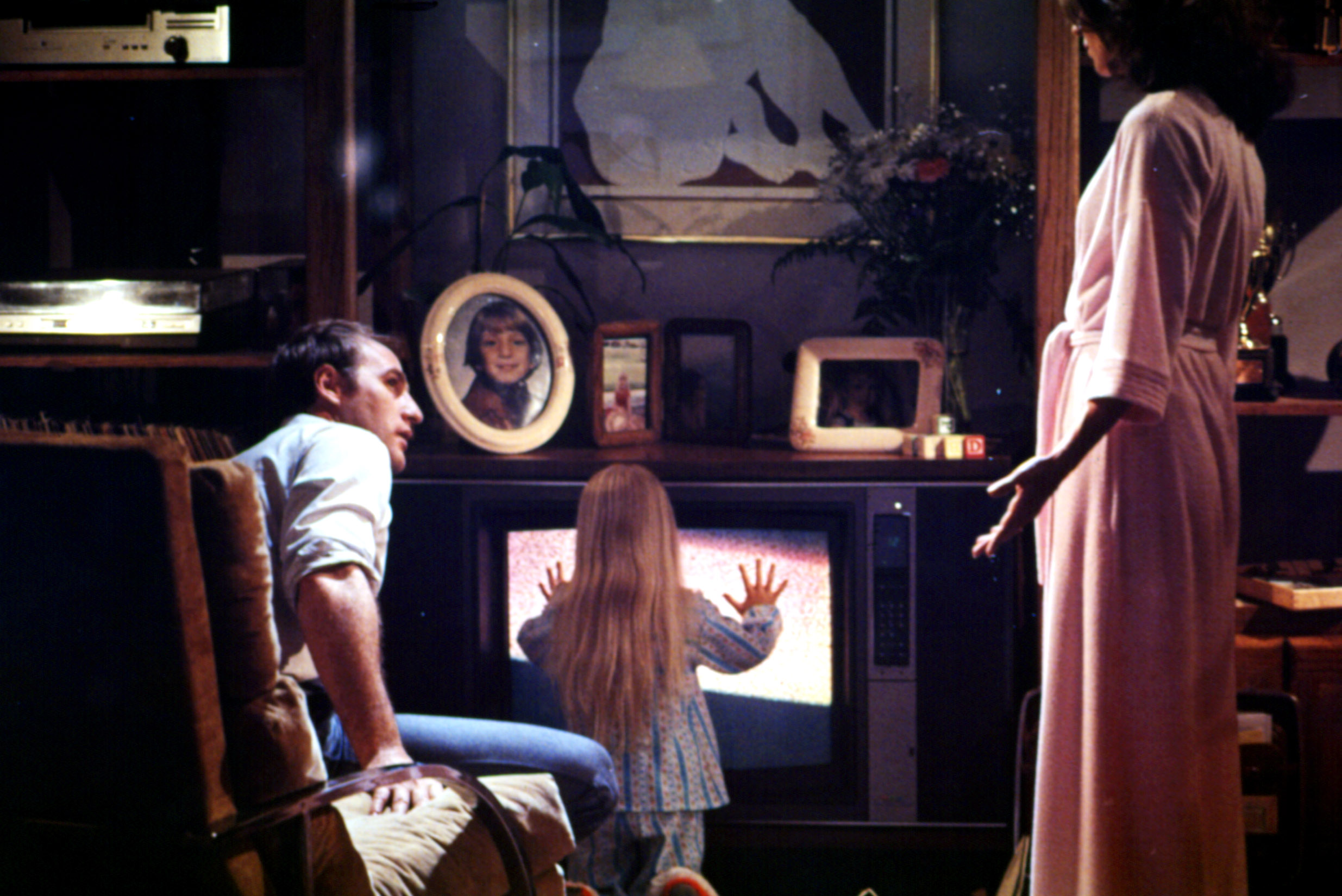 Craig T. Nelson, Heather O'Rourke, Jobeth Williams sit around a TV set that’s glowing in Poltergeist